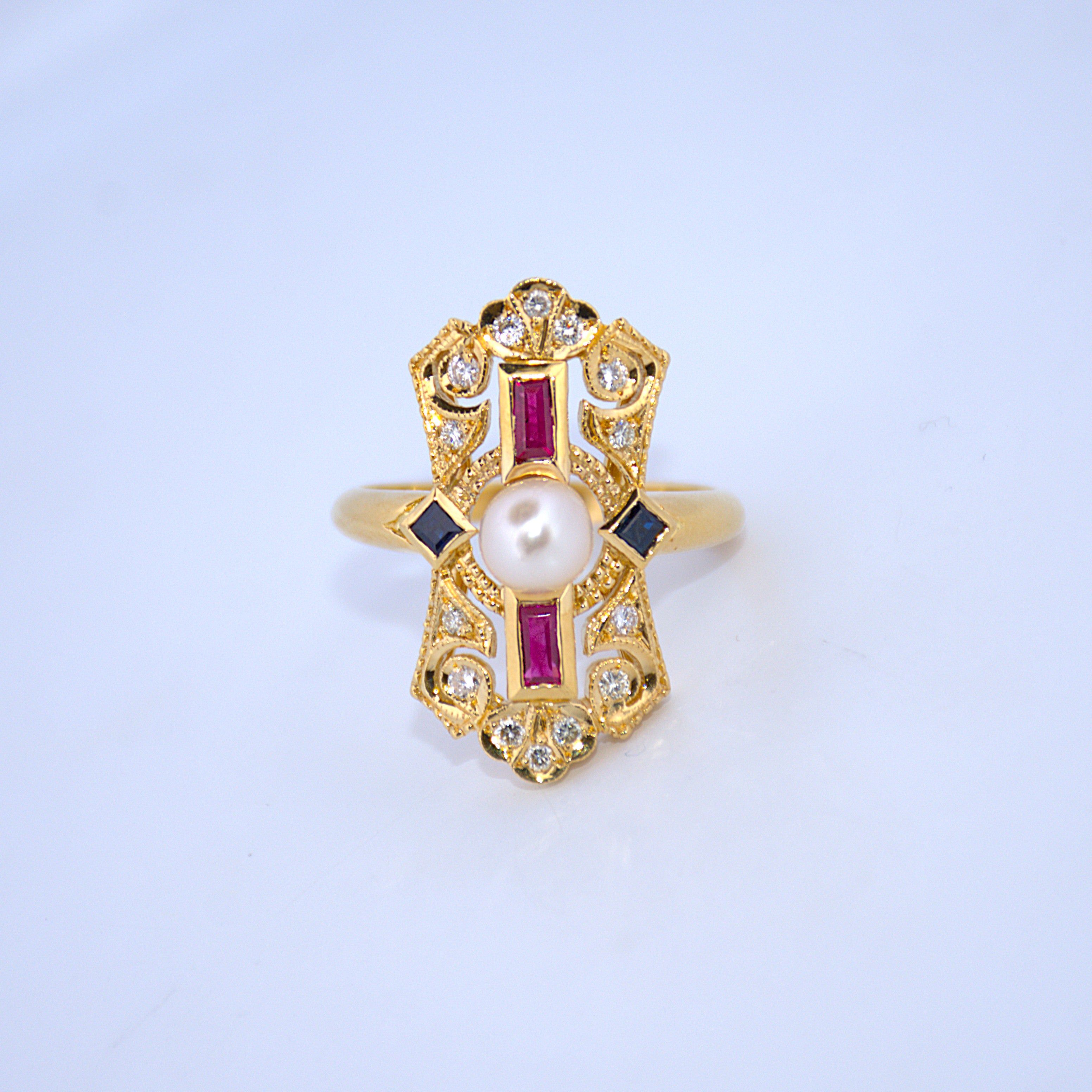 Gold ring with a pearl and red gemstones on a light blue background