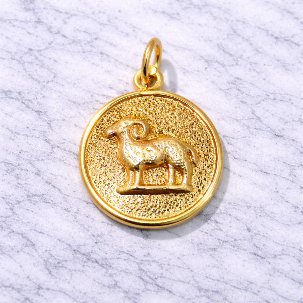 19.2K Portuguese Gold zodiac pendant with Aries goat symbol on a marble surface