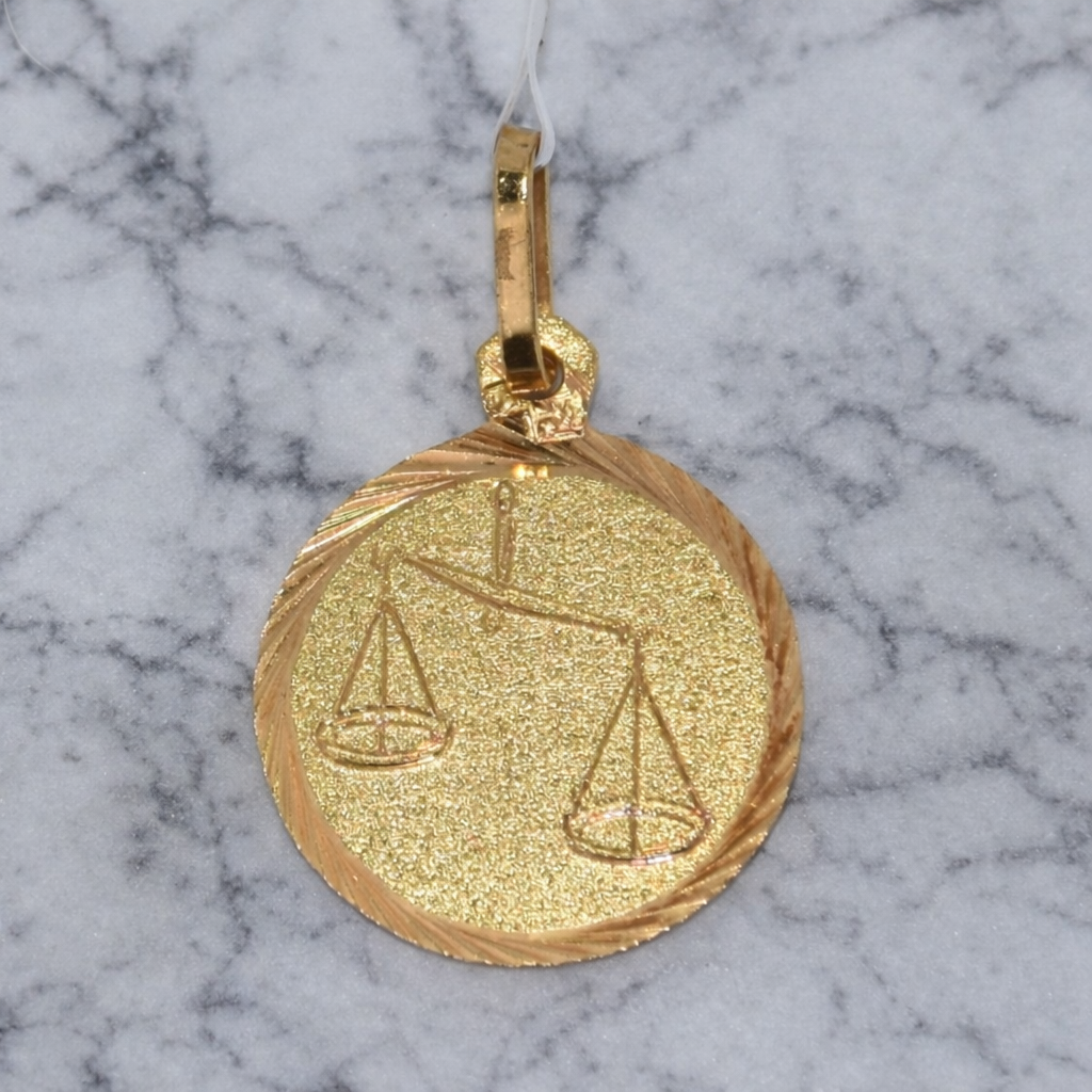 19.2K Portuguese Gold pendant with a Libra zodiac symbol on a marble background