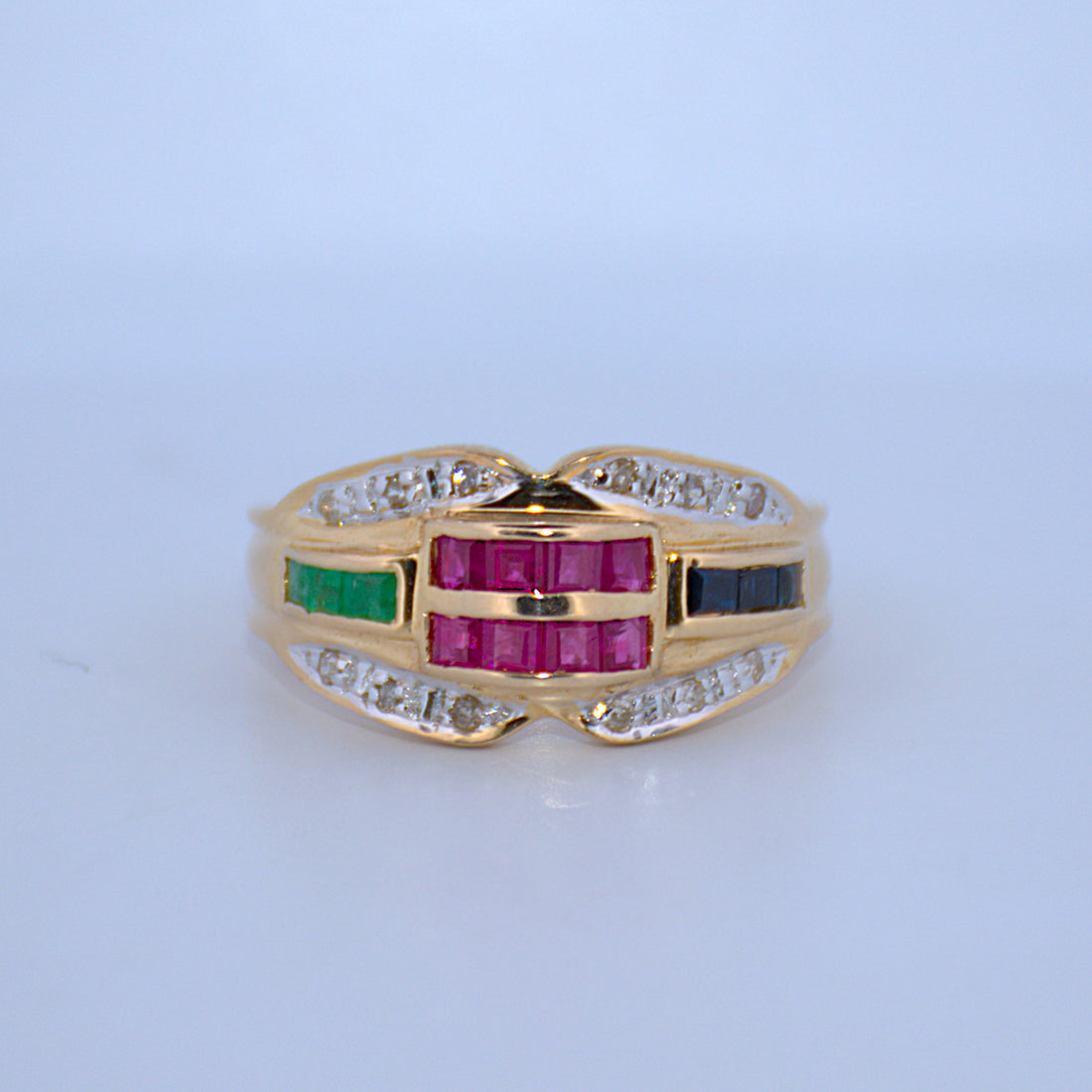 Gold ring with colored gemstones on a light blue background