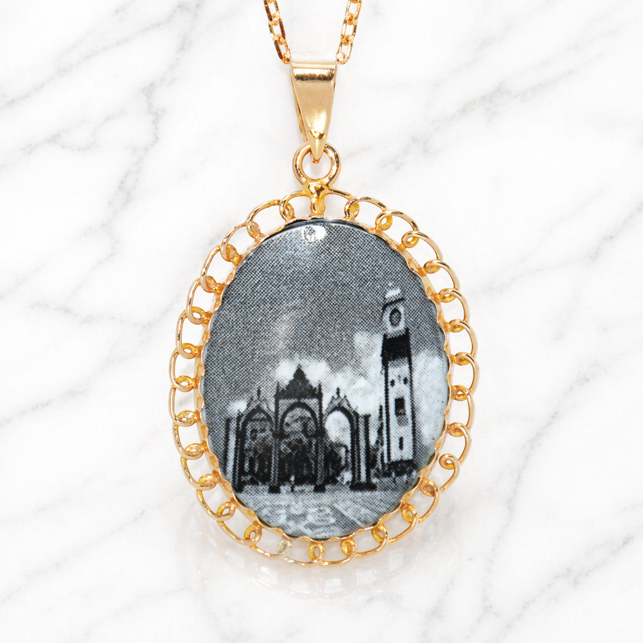 19.2K Portuguese Gold | Santo Cristo " Holy Christ " Pendants Gold-framed pendant with a black and white image of a building on a white background