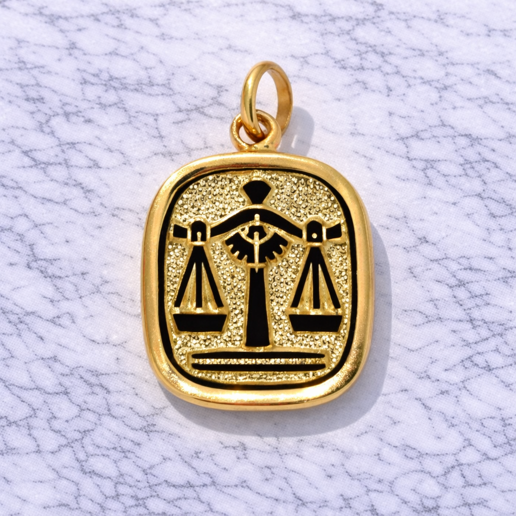 19.2K Portuguese Gold pendant with black Libra symbol on a white marble background