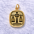 19.2K Portuguese Gold pendant with black Libra symbol on a white marble background