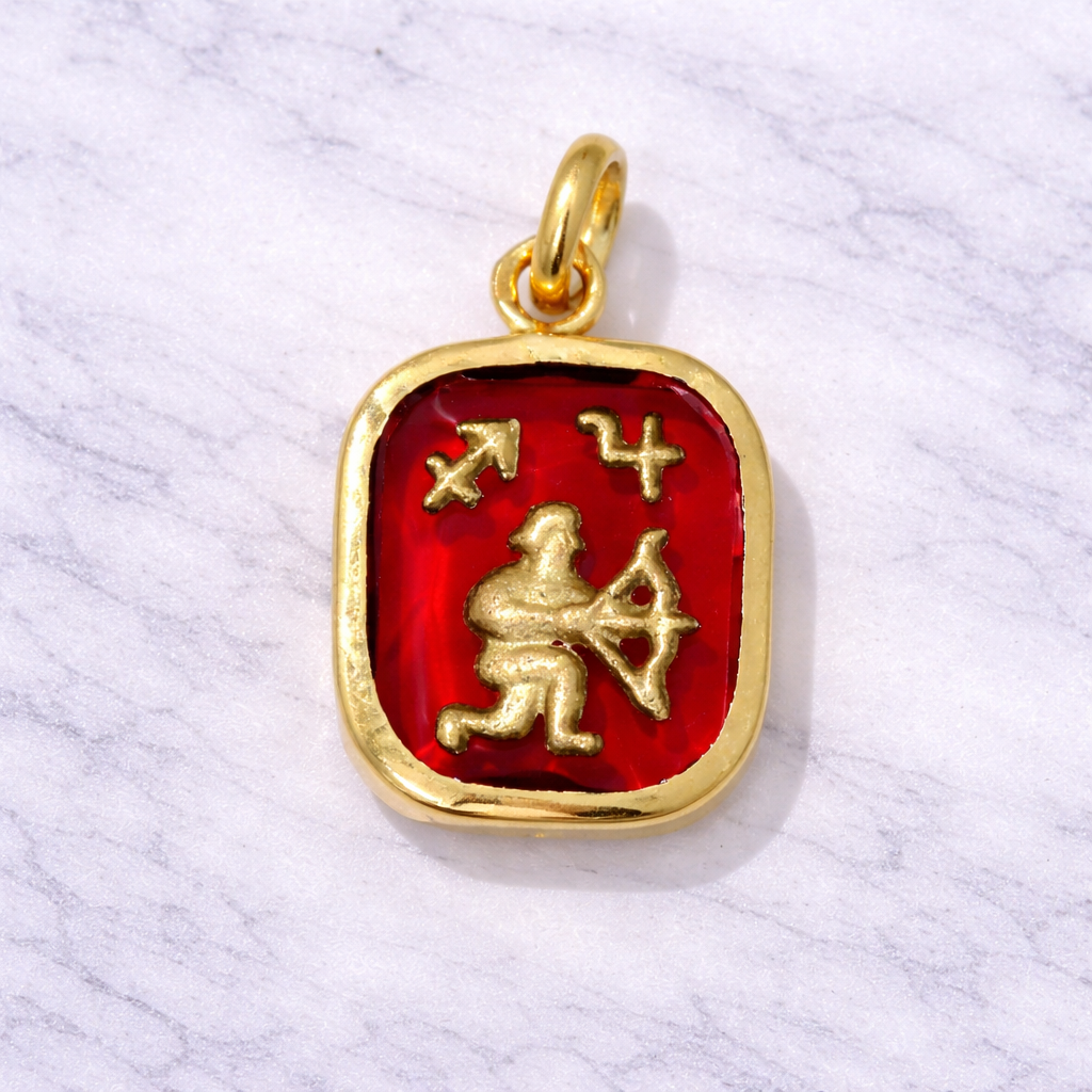 19.2K Portuguese Gold pendant with red stone featuring Sagitarrius astrological design on a white marble background
