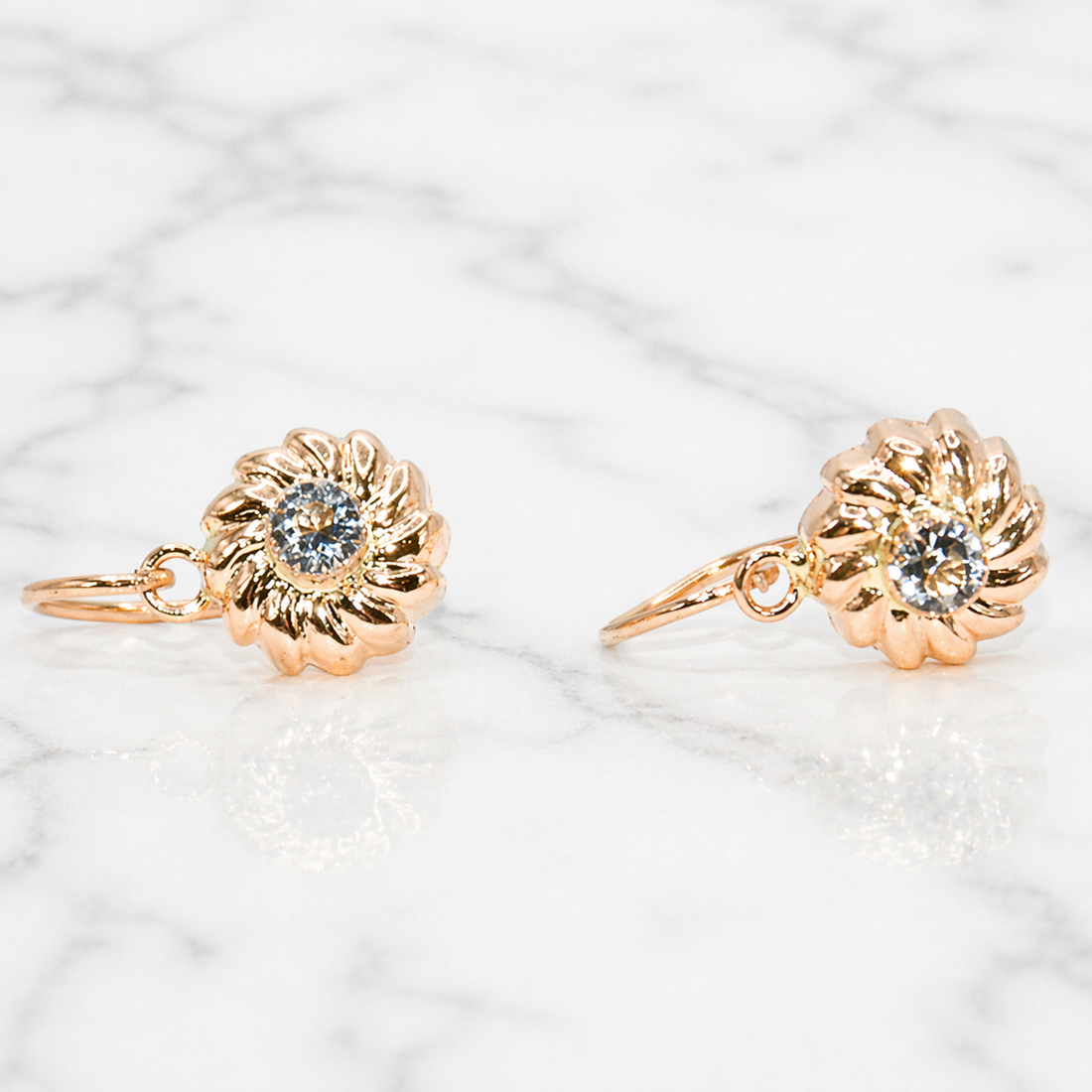 19.2K Portuguese Gold floral earrings with gemstones on a marble surface