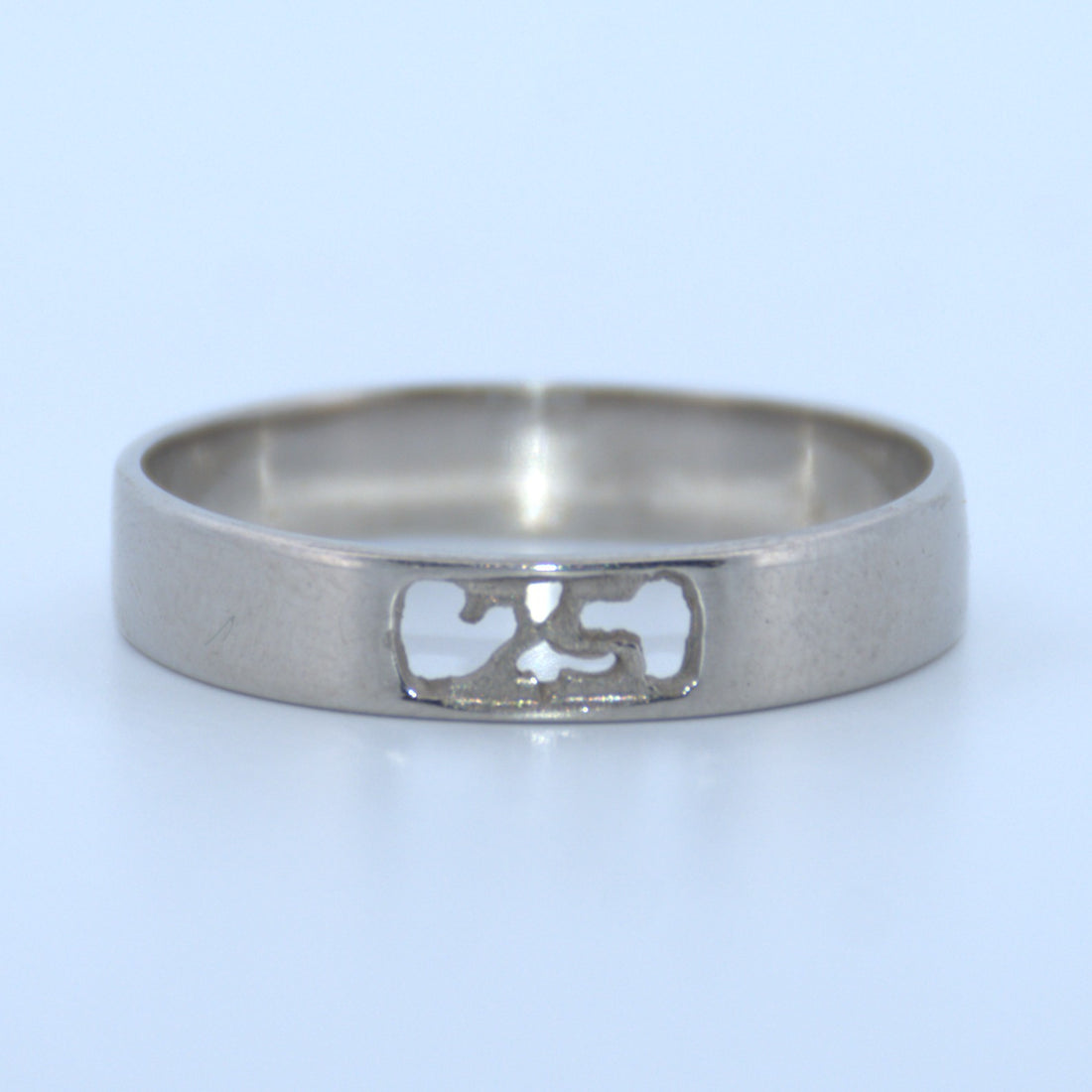 Silver ring with a cut-out design on a light blue background