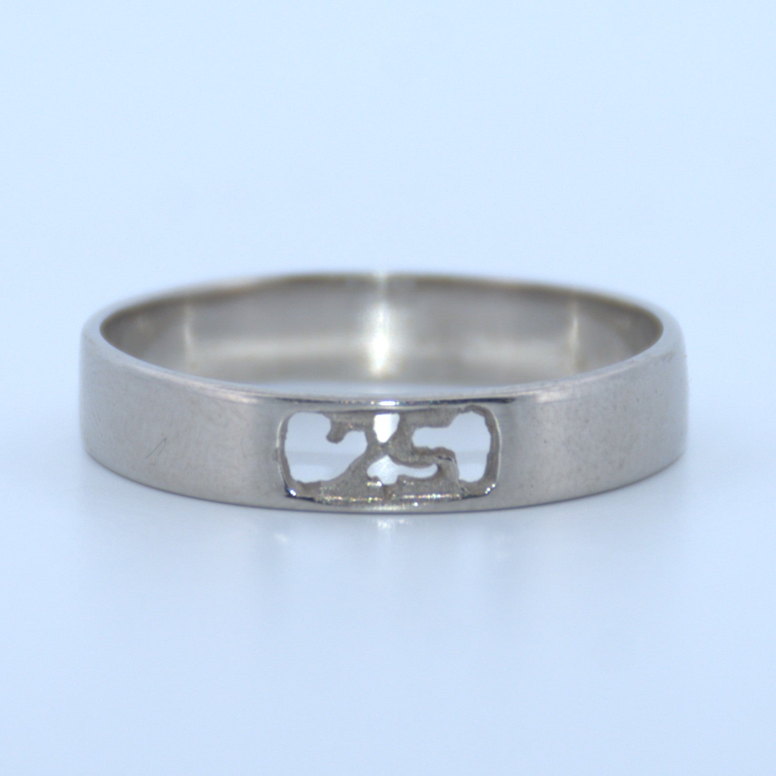 Silver ring with a cut-out design on a light blue background