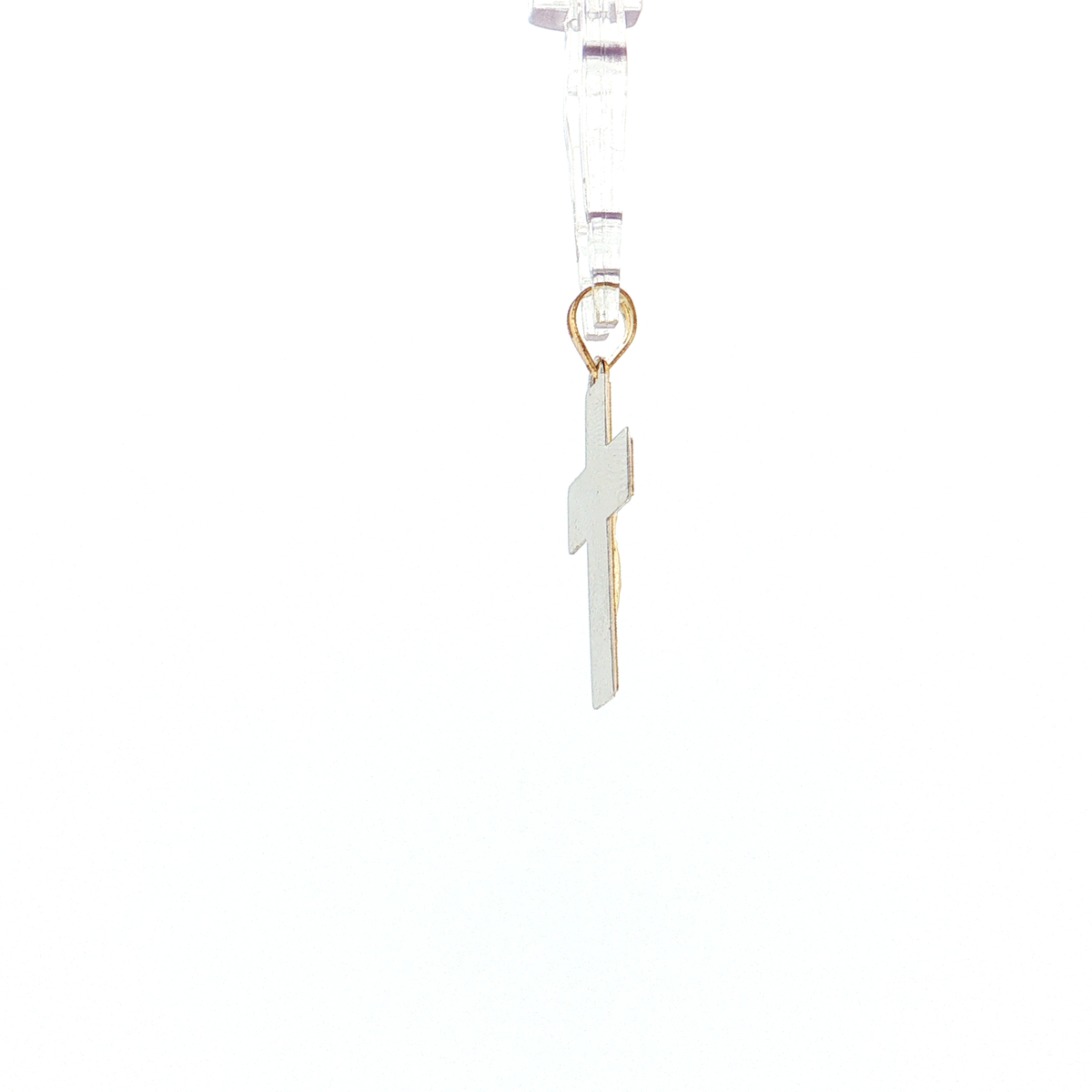 A small white enamel cross pendant with gold-tone metal trim and a gold ring, hanging from a clear plastic display loop against a plain white background.