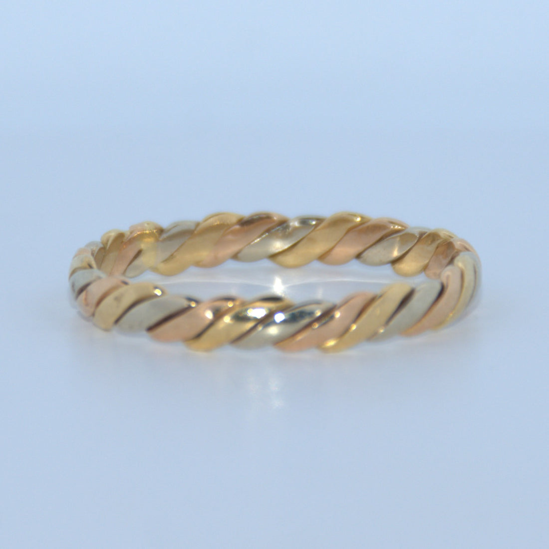 Gold ring with a twisted design on a light blue background