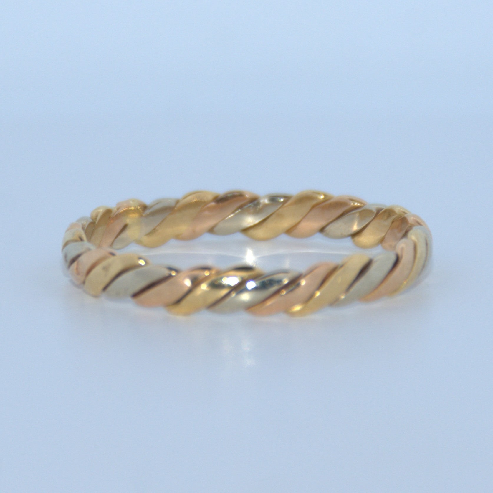 Gold ring with a twisted design on a light blue background