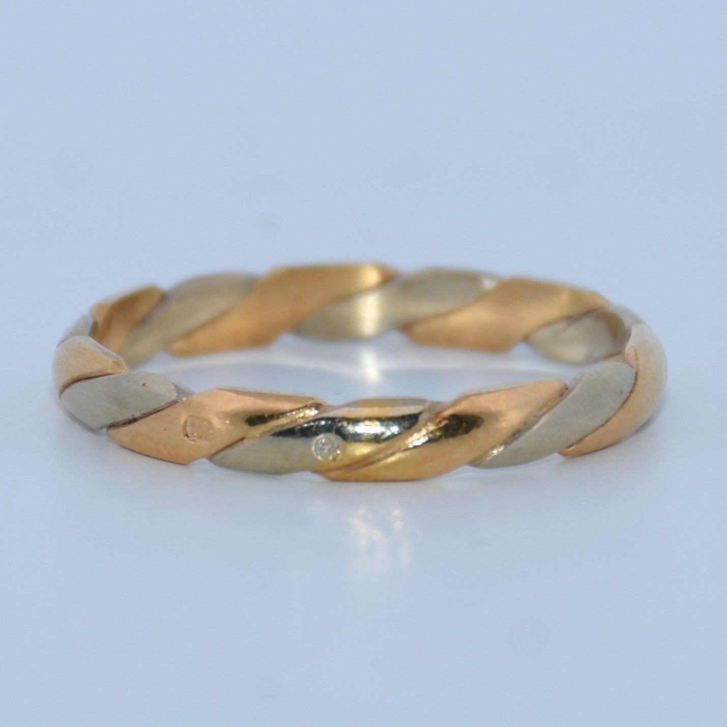 Three-tone gold ring on a light blue background