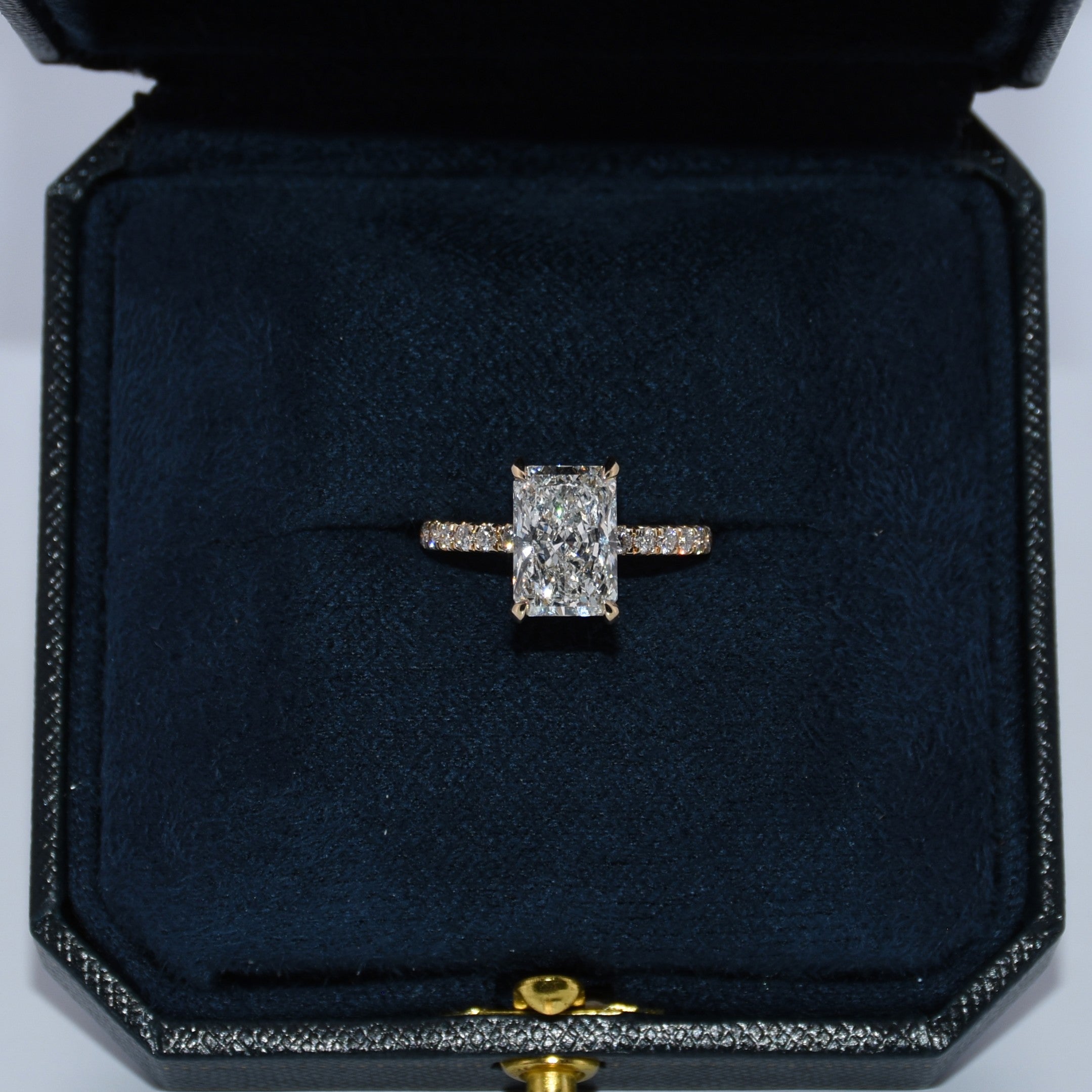 Diamond ring in a dark blue jewelry box on a light gray background