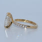 Gold ring with a large central diamond and smaller diamonds on the band against a light gray background