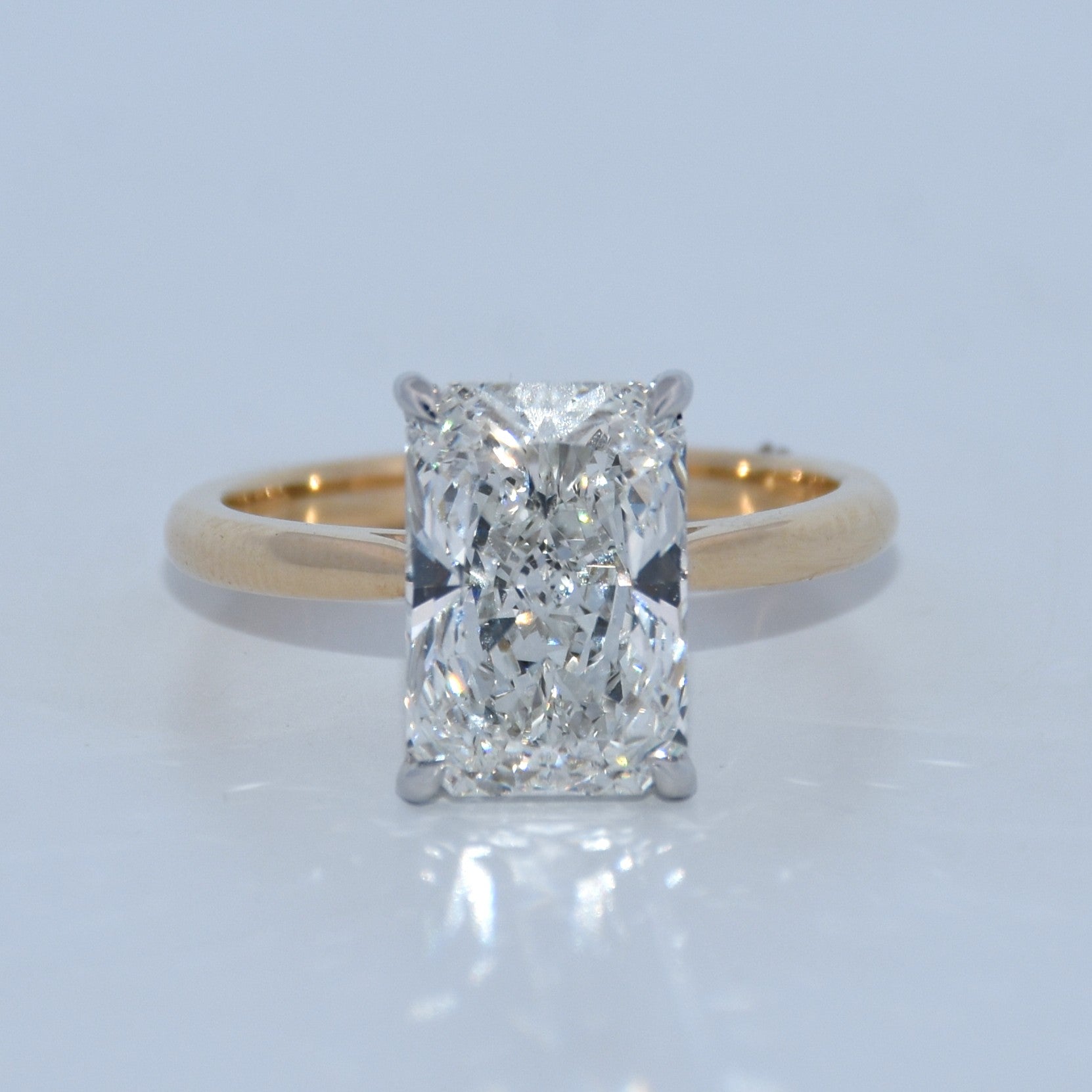 Gold ring with a large diamond on a light gray background