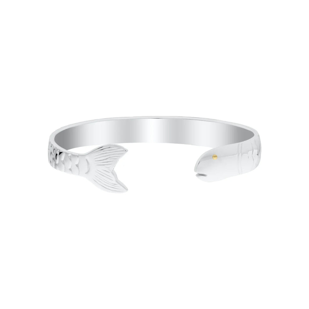 A polished silver cuff bracelet shaped like a fish, featuring a detailed scaled tail on one end and a small gold eye on the other, set against a plain white background.
