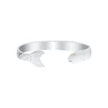 A polished silver cuff bracelet shaped like a fish, featuring a detailed scaled tail on one end and a small gold eye on the other, set against a plain white background.