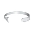 A silver-toned cuff bracelet shaped like a whale, featuring a whale tail on one end and a whale head on the other, with a tiny gold eye detail, shown on a plain white background.