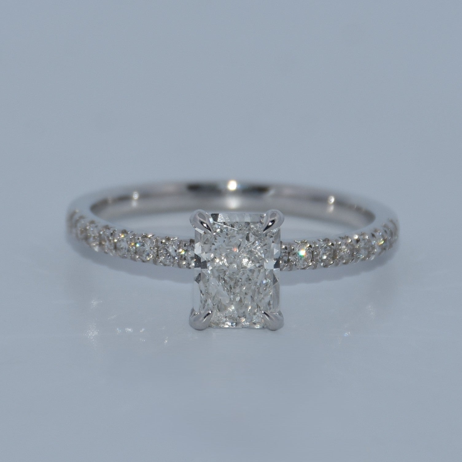 Diamond ring with a rectangular center stone on a light gray background