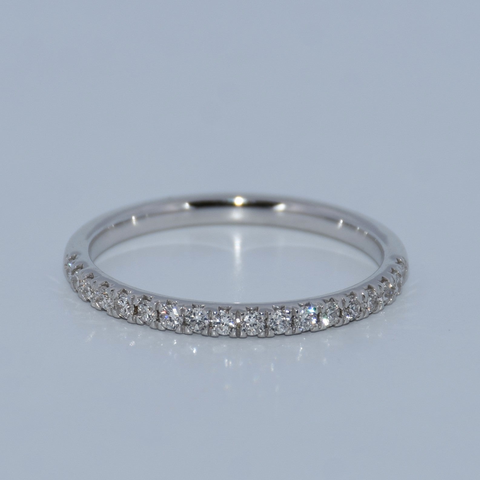 Silver ring with small diamonds on a light gray background