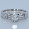 Diamond ring with a central diamond and baguette-cut side stones on a light gray background