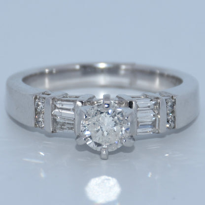 Diamond ring with a central diamond and baguette-cut side stones on a light gray background