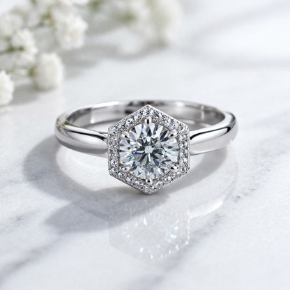 Silver ring with a diamond on a marble surface with white flowers in the background