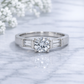 Diamond ring with baguette side stones on a marble surface with white flowers.