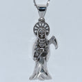 Silver pendant with a skeleton figure holding an owl on a white background