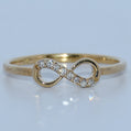 Gold infinity ring with diamonds on a light gray background