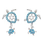 A pair of silver-toned turtle drop earrings embellished with bright blue rhinestones, shown on a plain white background.