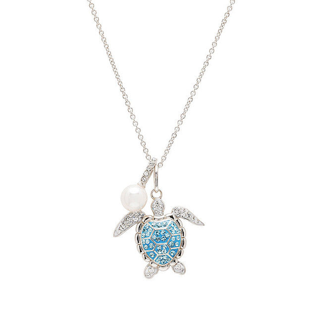 A silver-toned sea turtle pendant necklace with a light blue patterned shell, a white pearl bead, and small clear rhinestone accents on a white background.