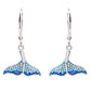 A pair of silver leverback dangle earrings featuring mermaid tail charms embellished with blue gradient rhinestones, shown against a plain white background.