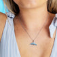 Woman wearing a necklace with a whale tail pendant