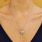 A silver-toned sea turtle pendant necklace with a green center, worn on a model's neck over a dark navy V-neck top.