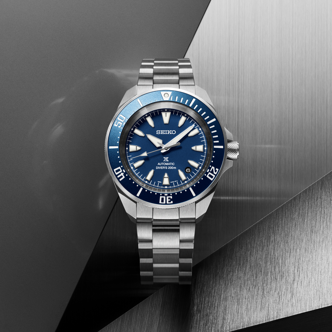 Seiko watch with blue dial and silver bracelet on a metallic background