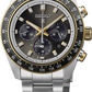 A Seiko wristwatch with a stainless steel link bracelet, featuring a dark gray dial, gold-tone accents on the bezel and crown, and a black tachymeter bezel.