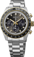 A Seiko wristwatch with a stainless steel link bracelet, featuring a dark gray dial, gold-tone accents on the bezel and crown, and a black tachymeter bezel.