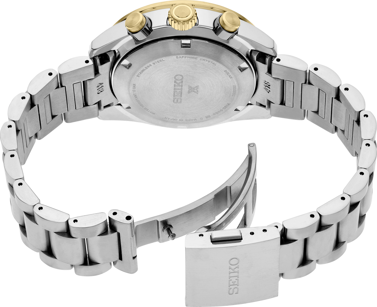 Rear view of a Seiko stainless steel watch with a gold-tone crown, showing the branded metal case back and linked bracelet on a white background.