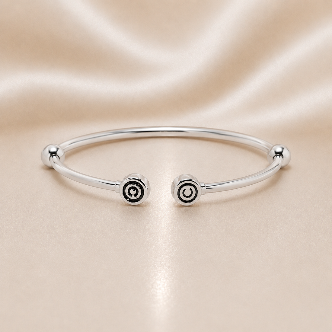 Silver bracelet with spiral designs on a beige satin background Sterling Silver | CHAM Bypass Charm Bangle Bracelet