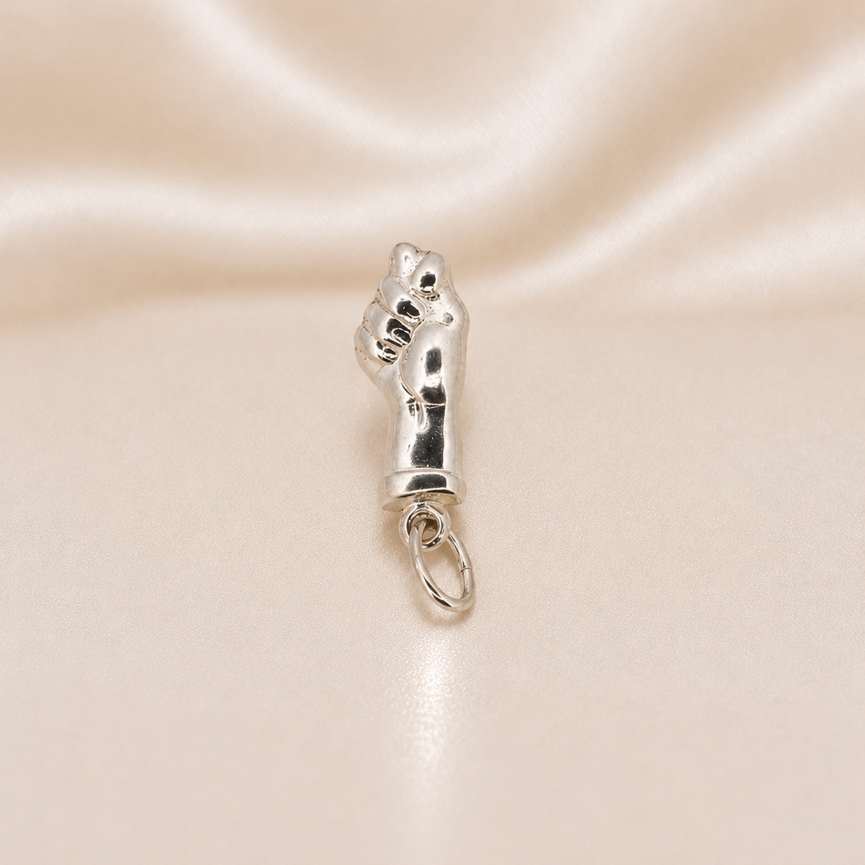Silver charm shaped like a paw on a satin background Sterling Silver | Fist Good Luck Charm Pendant