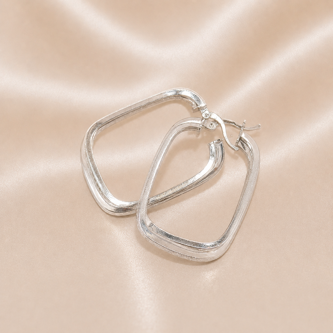 Silver hoop earrings on a pink satin background Sterling Silver | Oval Greek Key Design Hoops