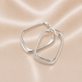 Silver hoop earrings on a pink satin background Sterling Silver | Oval Greek Key Design Hoops