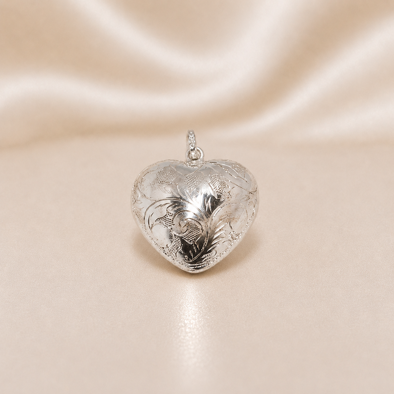 Silver heart-shaped pendant on a beige satin background Sterling Silver | Puffy Heart Pendant