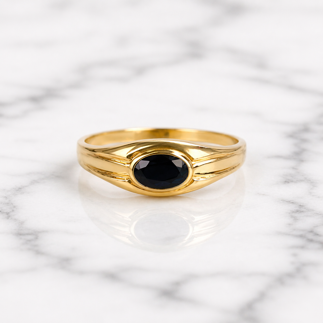 Gold ring with a black gemstone on a marble background