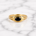 Gold ring with a black gemstone on a marble background