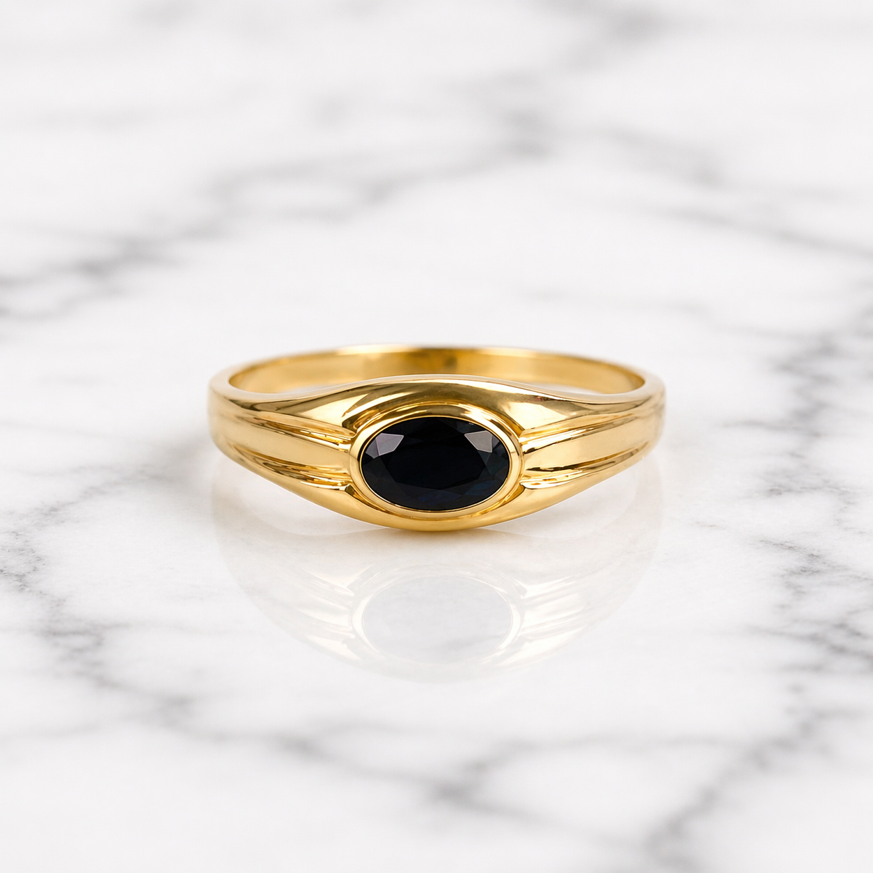 Gold ring with a black gemstone on a marble background