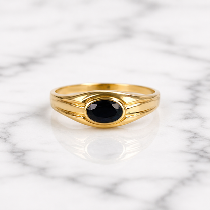 Gold ring with a black gemstone on a marble background