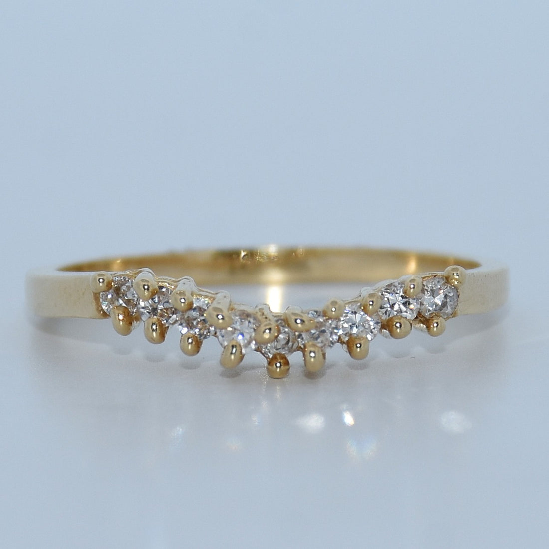 Gold ring with small diamonds on a light gray background