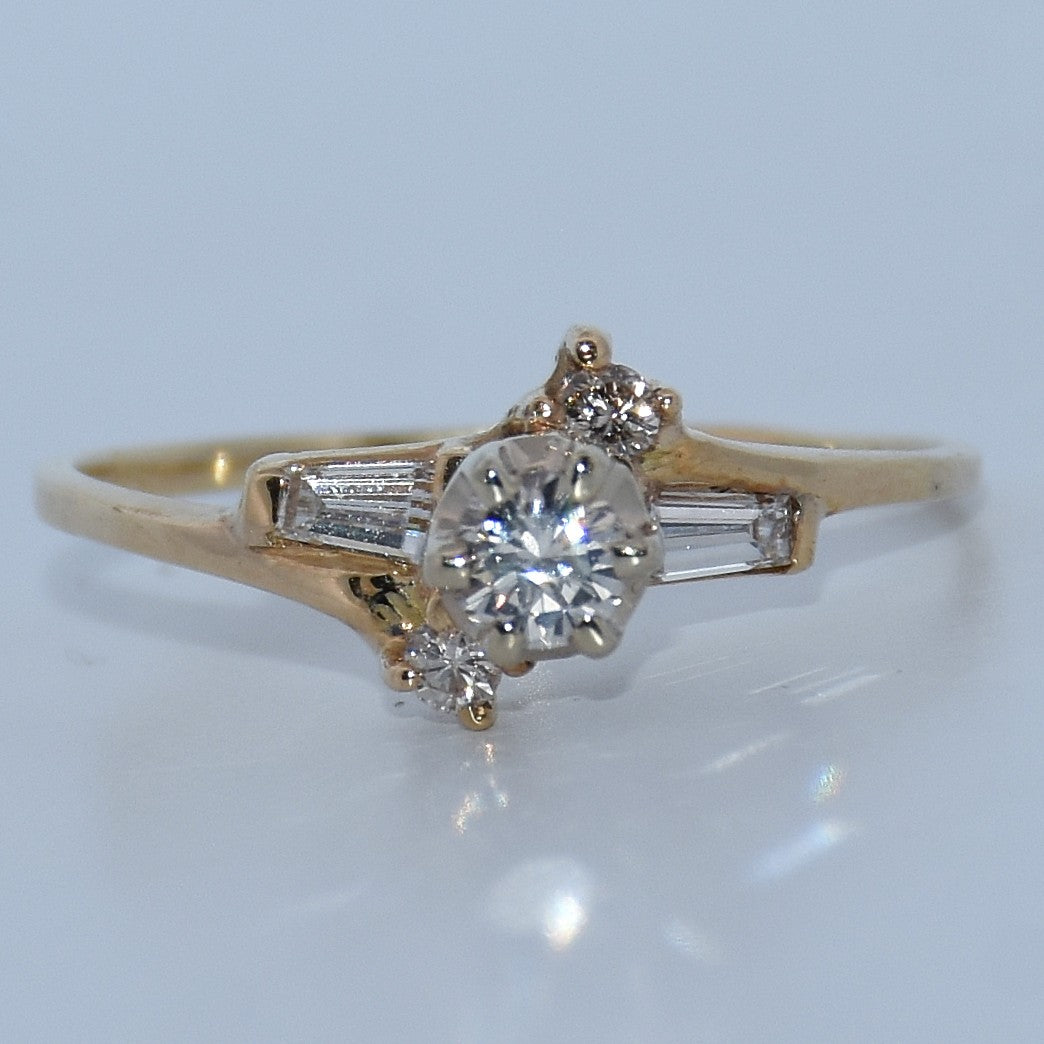 Gold ring with a diamond and baguette-cut stones on a light gray background