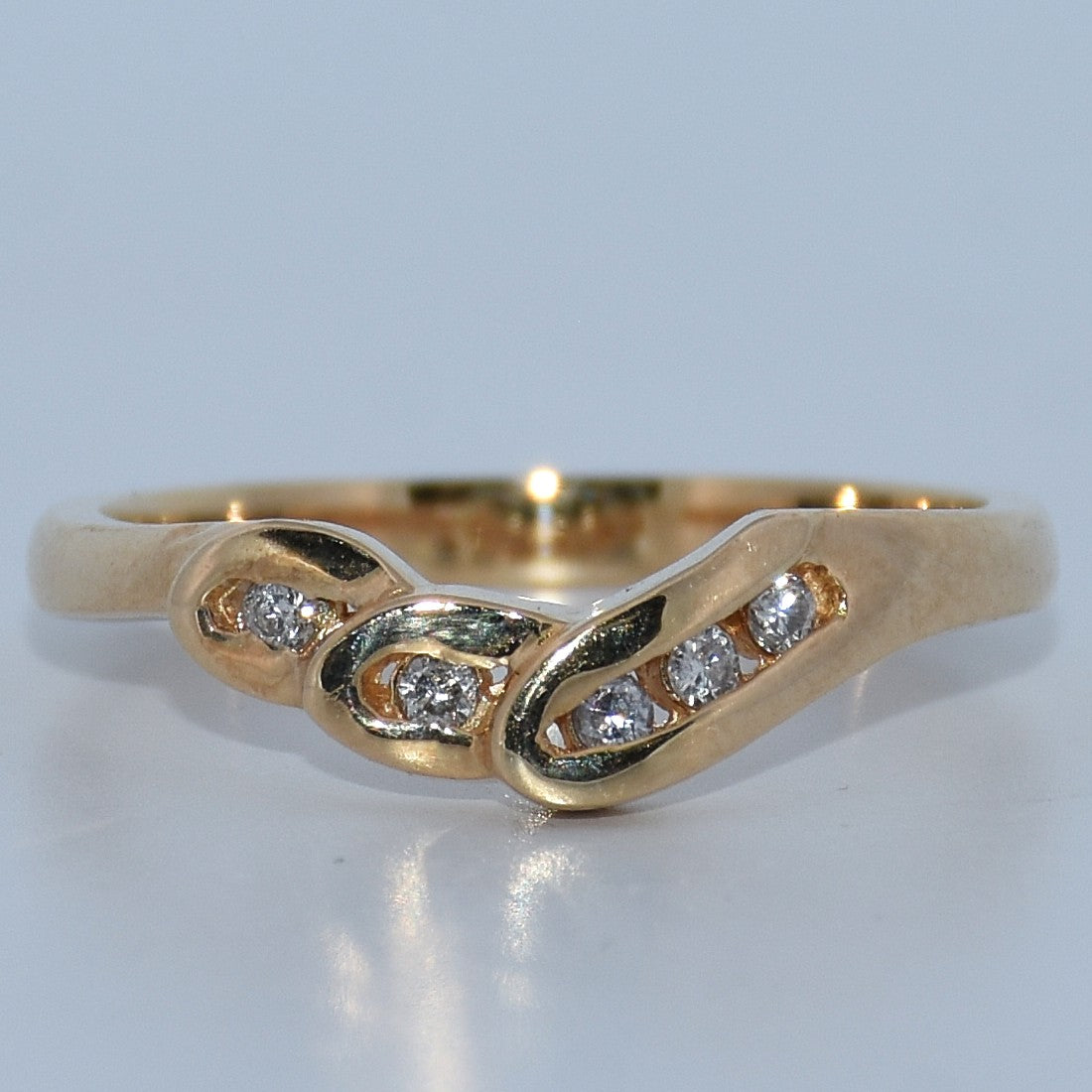 Gold ring with diamond accents on a light gray background